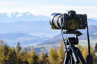 DSLR Camera on Tripod with Mountain Landscape Background