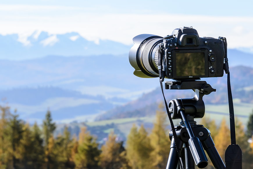 DSLR Camera on Tripod with Mountain Landscape Background