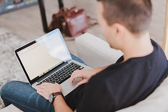 Man working on laptop sitting on couch at home