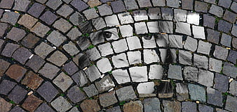 Surreal face emerging from cobblestone pavement texture