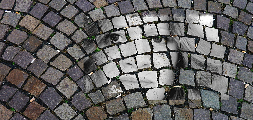 Surreal face emerging from cobblestone pavement texture