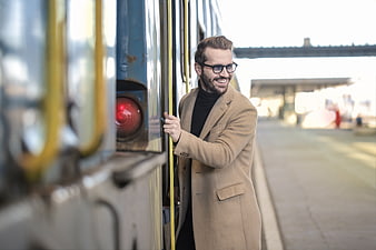 Smiling man in beige coat boarding train at station