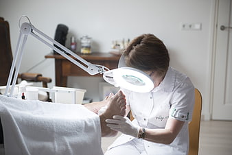 Podiatrist examining patient's foot with magnifying lamp in clinic