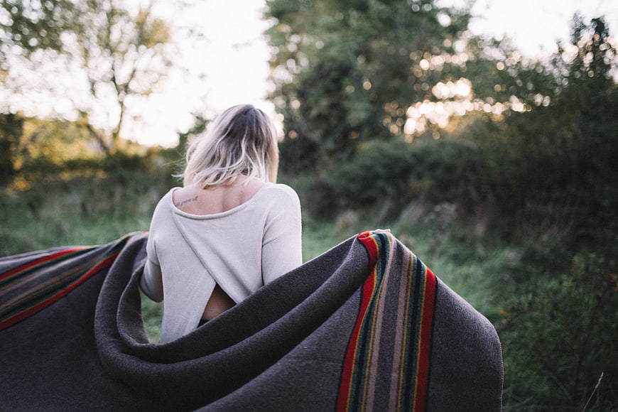 Woman wrapped in blanket walking in nature