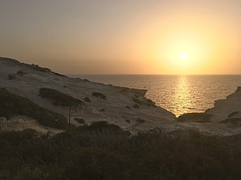 Golden sunset over calm ocean and coastal cliffs