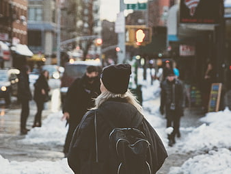 Woman in Winter Coat Walking on Snowy City Street