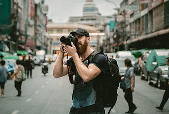 Male Photographer with DSLR Camera on Busy City Street