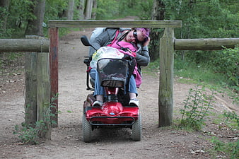 Woman in mobility scooter passing through wooden gate in forest