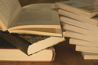 Stack of vintage books with open pages on wooden table