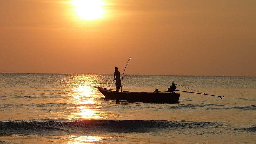Silhouette of Fisherman on Boat at Golden Sunset