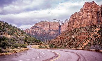 Winding Road Through Red Rock Canyon with Snow-Capped Peaks