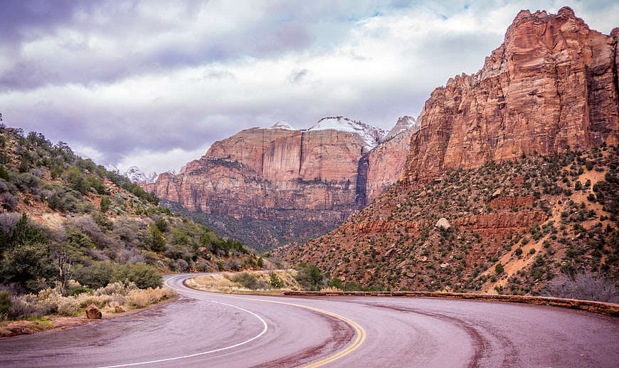 Winding Road Through Red Rock Canyon with Snow-Capped Peaks