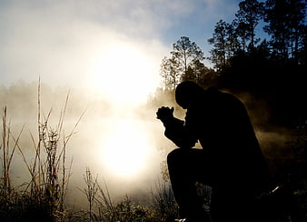 Silhouette of Man Praying in Misty Forest at Dawn