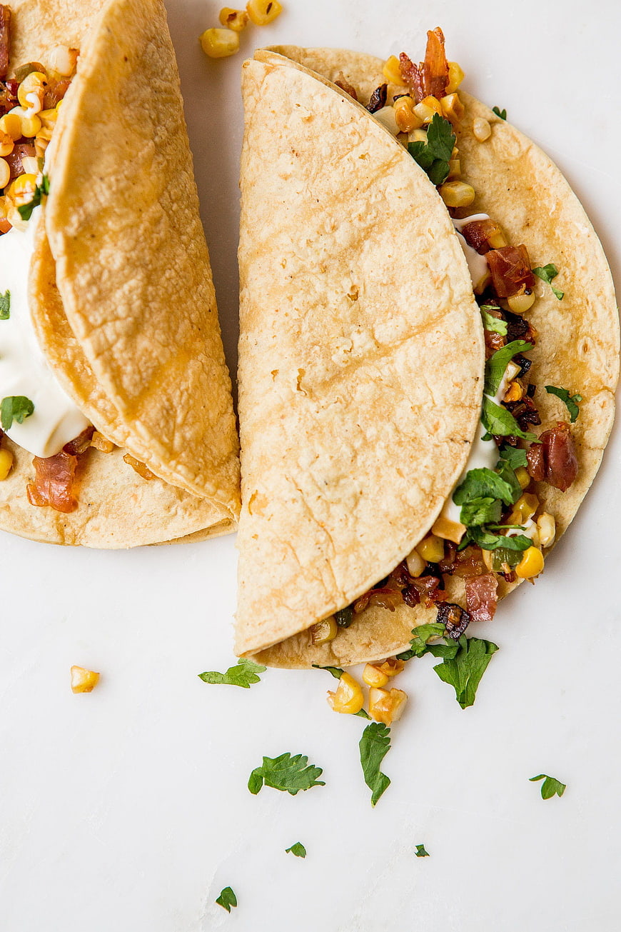 Overhead view of fresh corn and bacon tacos with cilantro