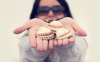 Woman holding seashells in cupped hands on beach