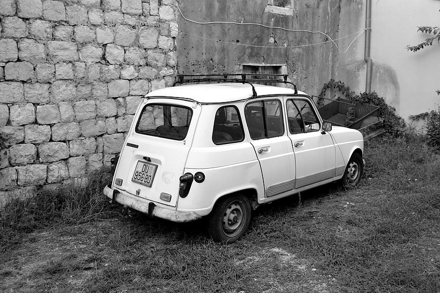 Vintage White Fiat 600 Multipla Parked by Stone Wall