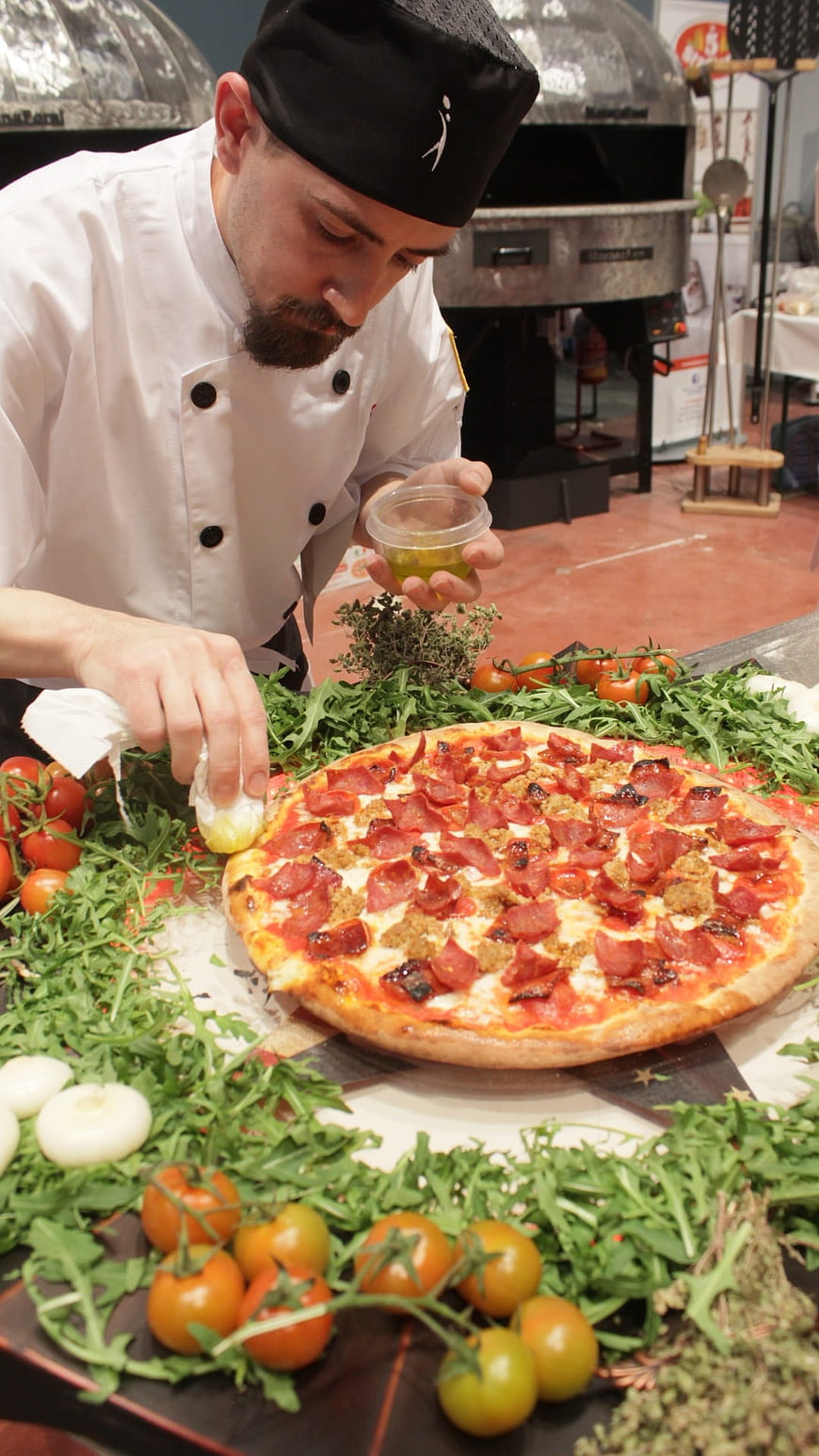 Chef preparing pepperoni pizza with fresh ingredients