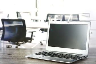 Silver laptop on wooden desk in blurred office background