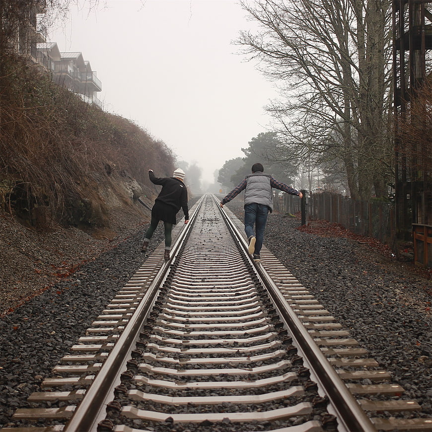 Two friends walking away on foggy railroad tracks