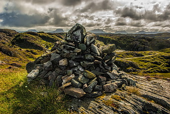 Stone Cairn on Rocky Hilltop with Dramatic Cloudy Sky