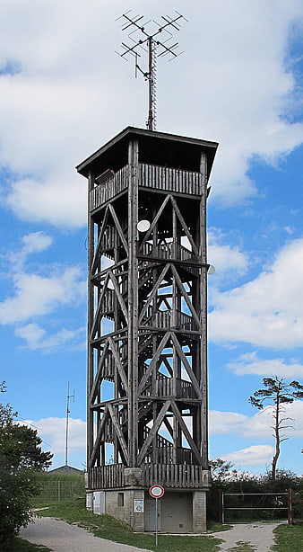 Tall wooden observation tower with antenna against blue sky