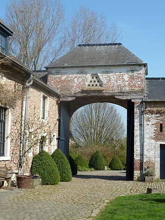 Rustic brick archway entrance to a historic European farmhouse courtyard
