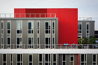 Modern gray and red office building facade with balcony