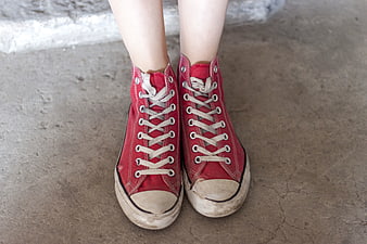 Close-up of worn red high-top sneakers on concrete