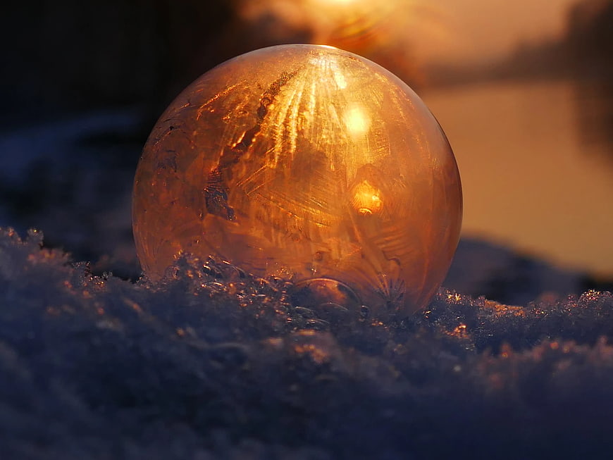 Golden Ice Crystal Sphere in Snow at Sunset