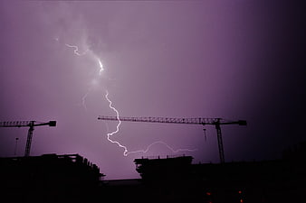 Dramatic lightning strike over construction cranes at night