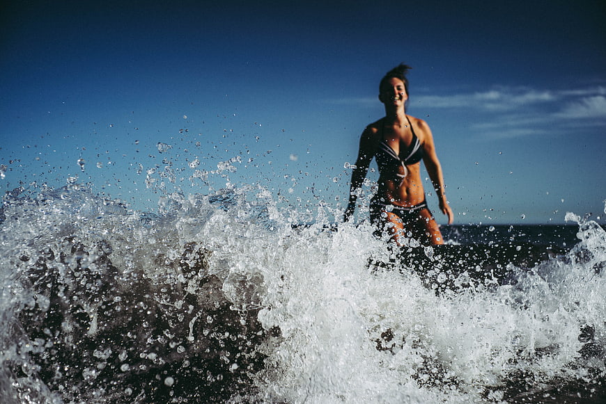 Woman in Bikini Splashing in Ocean Waves