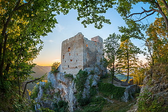 Ancient stone castle ruins on a rocky cliff at sunset
