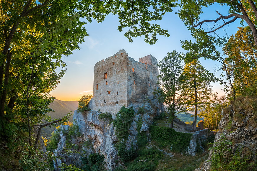 Ancient stone castle ruins on a rocky cliff at sunset