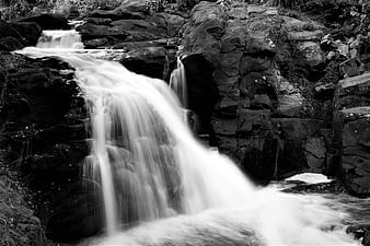 Black and white long exposure waterfall cascading over dark rocks