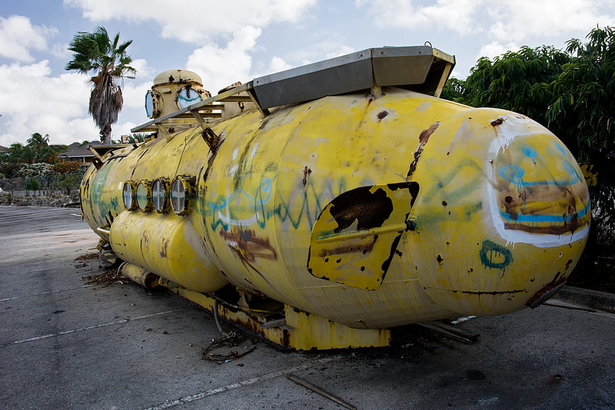 Rusty yellow submarine on pavement with graffiti