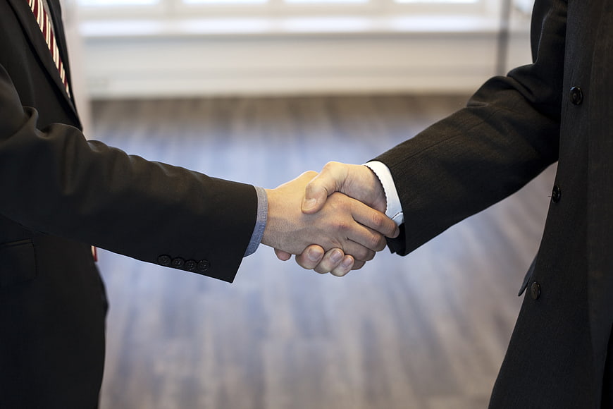 Businessmen shaking hands in suits close up