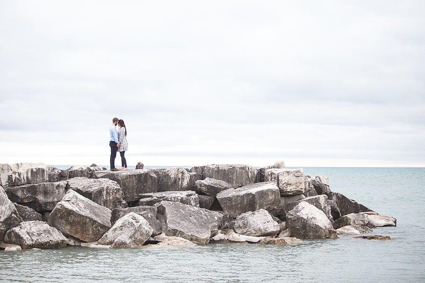 Couple standing on rocky jetty by the ocean