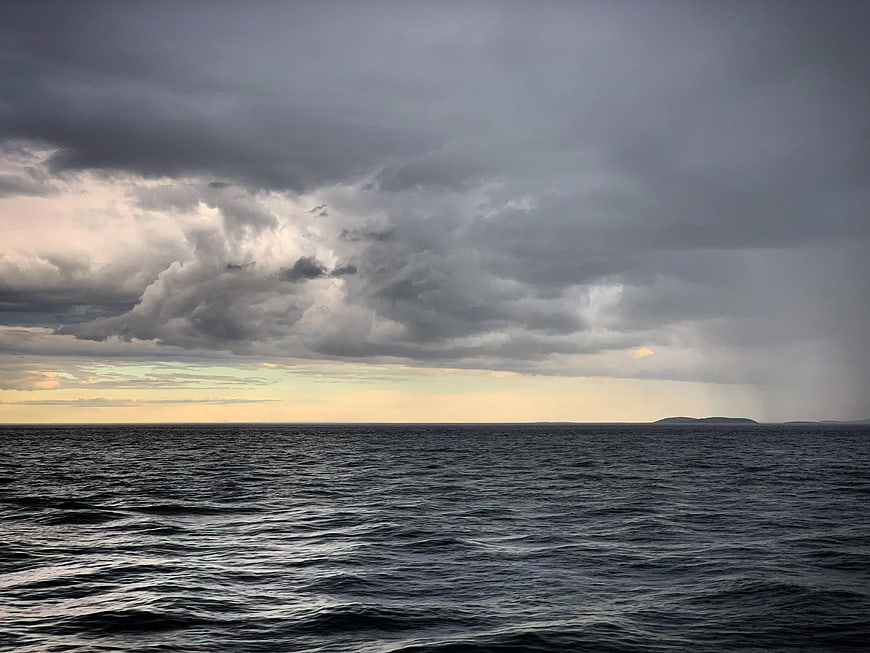Dramatic Stormy Ocean Sky with Rain and Distant Island