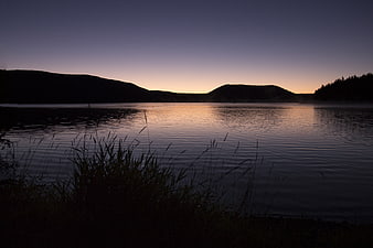 Serene Lake Sunset with Mountain Silhouettes and Mist