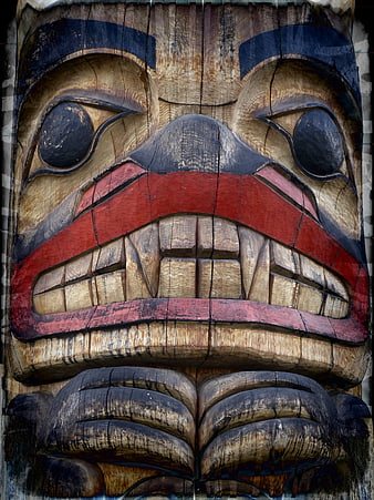 Close-up of carved wooden totem pole face with red and black paint