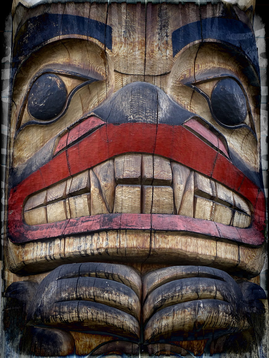 Close-up of carved wooden totem pole face with red and black paint