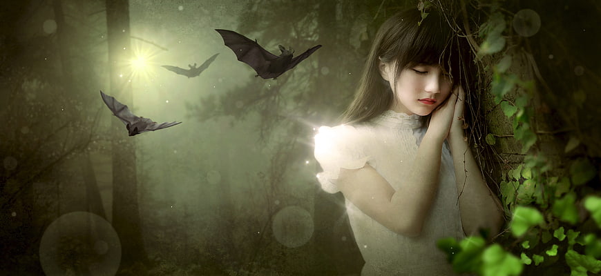 Mystical girl in white dress with bats in dark forest