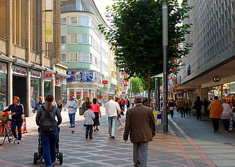 Busy European pedestrian shopping street with diverse passersby and storefronts