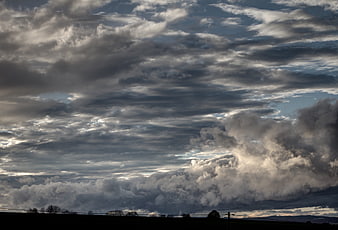 Dramatic storm clouds over dark silhouetted landscape