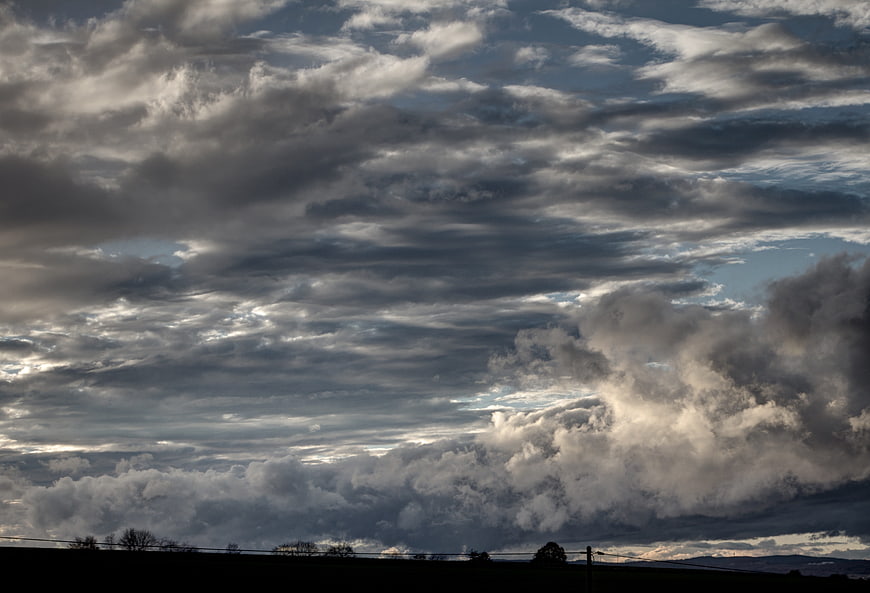 Dramatic storm clouds over dark silhouetted landscape