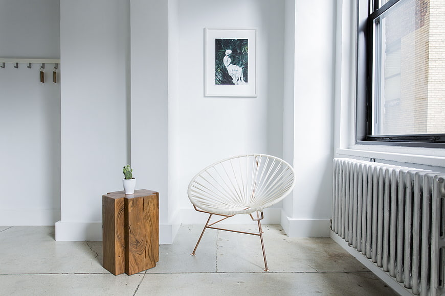 Modern white interior with Acapulco chair and wooden side table