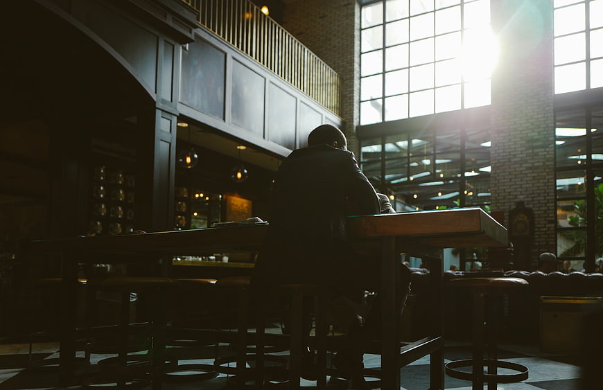 Silhouette of man sitting at bar counter in sunlit cafe