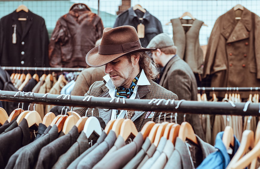 Man in Fedora Browsing Vintage Clothing Racks