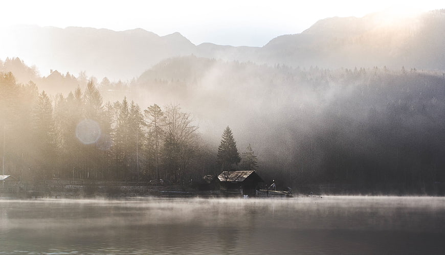 Misty Morning Lake with Cabin and Mountains