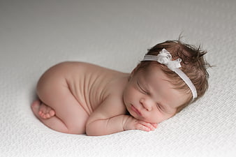 Sleeping Newborn Baby Girl Wearing White Headband on Gray Background